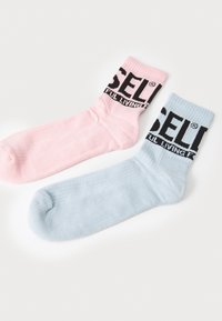 Due coppie di calzini crew: una rosa e una azzurra chiaro, con testo nero a contrasto sui polsini che recita "FUL LIVING." Texture morbida e a coste.
