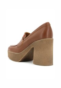Scarpe platform in pelle marrone con un tacco chunky beige, caratterizzate da una punta arrotondata e una superficie liscia, che mostrano linee pulite e dettagli minimi.