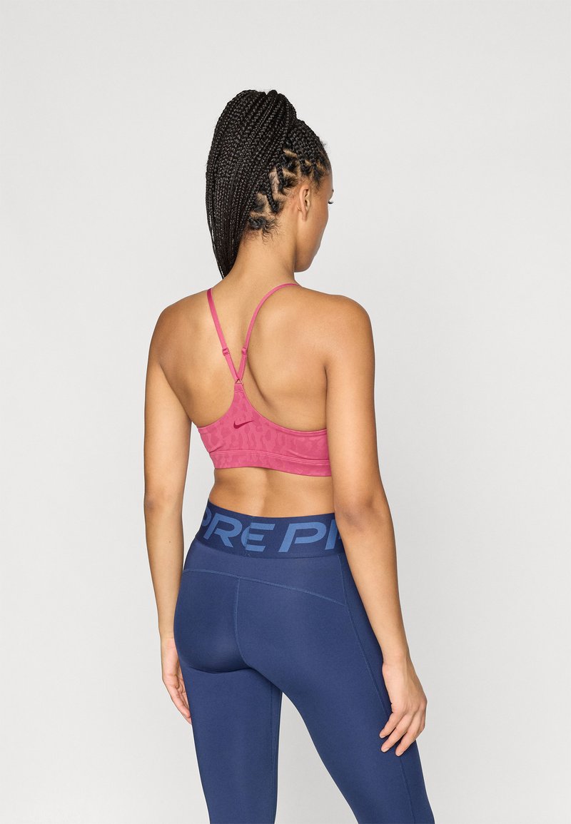 Sport bra in pink with textured pattern and adjustable straps, paired with navy leggings featuring a bold waistband design.