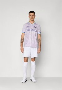 Hele lilla jalgpallivorm siniste detailidega, millel on "VONOVIA" logo, koos valgete lühikeste pükste ja sokkidega; kangas tundub siledalt ja hingav.