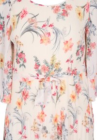 Robe fleurie avec manches courtes bouffantes, fond ivoire et taille ceinturée. Présente des motifs floraux vibrants en rose, jaune et bleu avec une finition texturée.