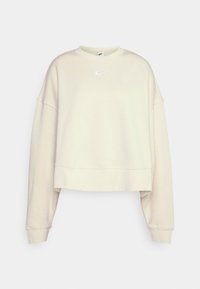 Sweatshirt court couleur crème en tissu doux, avec des manches longues et un petit logo Nike blanc sur la poitrine.