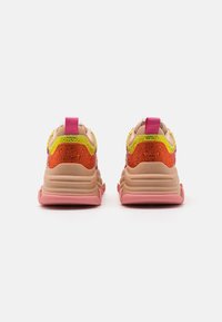 Baskets colorées avec une tige texturée ornée d'accents orange, rose et jaune, une semelle épaisse et un onglet de talon rose.