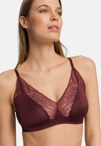 Bralette mauve en tissu lisse et mat avec un revêtement en dentelle florale sur les bonnets ; bretelles ajustables et détails à bords festonnés.