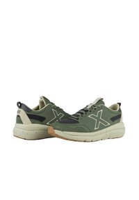 Zapatillas deportivas verdes con una parte superior texturizada, que presentan un gran logo blanco, una lengüeta acolchada y una suela beige con moteado.
