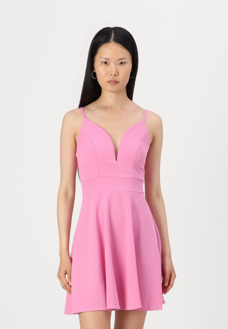 Ροζ αμάνικο φόρεμα με βαθύ V ντεκολτέ, εφαρμοστή σιλουέτα και φούστα που ανοίγει. Φτιαγμένο από απαλό, ελαφρύ ύφασμα με ελάχιστες ραφές.