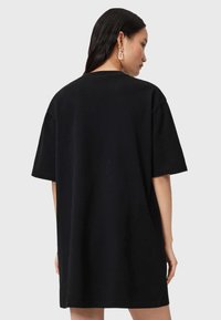 Camiseta negra de gran tamaño con mangas cortas, hecha de suave tela de algodón, con cuello redondo y dobladillo recto. Diseño minimalista.