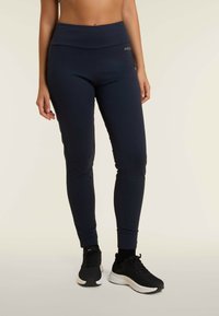 Leggings atletici blu navy con tessuto morbido, vita alta e vestibilità slim. Presentano un piccolo accento con logo dorato sul davanti.
