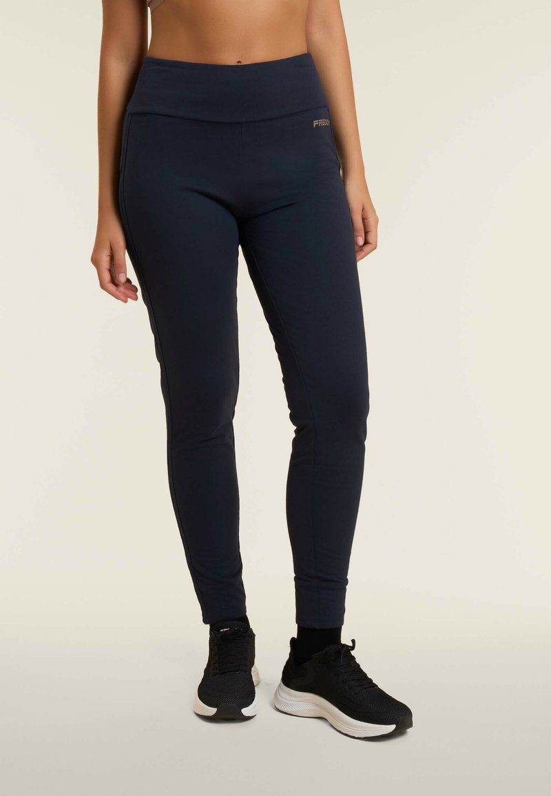 Leggings atletici blu navy con tessuto morbido, vita alta e vestibilità slim. Presentano un piccolo accento con logo dorato sul davanti.
