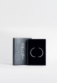 Silvriga ringörhängen med en pärldesign, presenterade i en box klädd med svart sammet och med en metallisk silvrig yta.