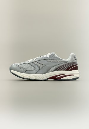 Pantof sportiv de culoare gri deschis, cu șireturi albe, partea superioară din plasă și accente vișinii pe toc și talpă, prezentat în profil pe un fundal gri.