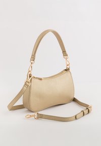 Beige tekstureret håndtaske med en kurvet form, guldhardware, et kort håndtag og en aftagelig lang rem. Har en lynlåslukning.