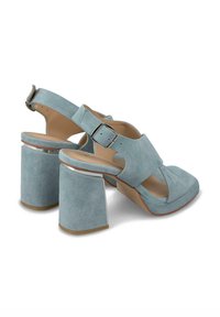 Sandalias de tacón azul de ante con punta cuadrada, correa ajustable con hebilla y tacones gruesos acentuados en plata. Textura suave y diseño de espalda abierta.