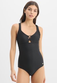 Maillot de bain noir à une pièce avec texture côtelée, bretelles larges, un détail en trou de serrure à l'avant et une petite accent doré au bas.