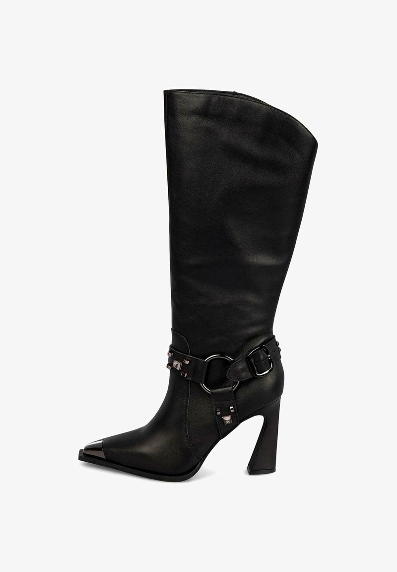 Bota de cuero negro hasta la rodilla con punta afilada, puntera metálica y cinturón decorativo con acentos de hardware en el tobillo. Tacón alto.