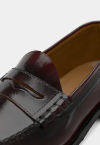 Burgundijas ādas loaferi ar gludu apdari, ar izšūtu akcentu un apaļu, gludu mocasīna stila dizainu.