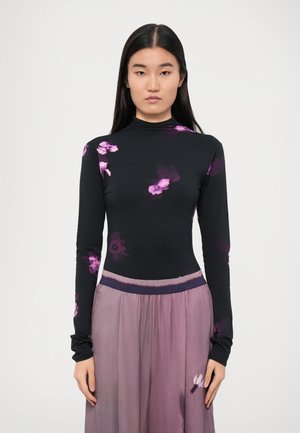 Long-sleeve black top with purple floral print, high neckline, paired with a flowing, lavender skirt featuring a soft texture and elastic waistband.