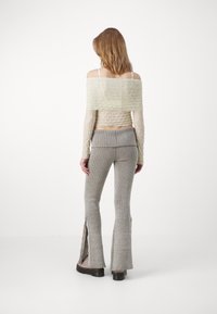 Off-white, ribbet strikket crop-top med lange ermer og teksturert finish, parret med grå stretch flared bukser med sidelukking og striper.
