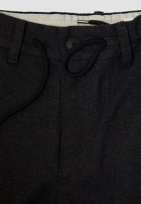 Zwarte, gestructureerde stoffen broek met een tailleband met trekkoord, vooraan knoopsluiting en contrasterende binnenvoering. Voorzien van zijzakken.