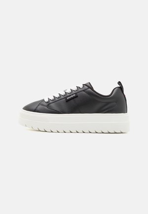 Sort lavtop sneaker med hvid tyk sål og snørebånd, med "HUGO" logo på siden.