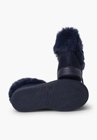 Stivali alla caviglia blu navy con trim in pelliccia sintetica, materiale scamosciato, suola piatta in gomma con motivo antiscivolo, accentuati da un dettaglio con fibbia laterale.