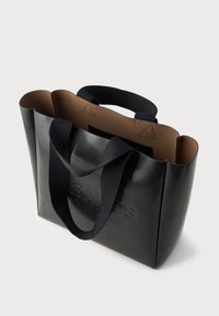 Bolsa tote preta com uma textura suave, apresentando lados estruturados, interior em contraste castanho e alças de tecido. Logótipo em relevo na parte da frente.