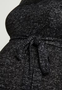 Tessuto grigio scuro, con texture e un motivo a macchie. Presenta un cinturino annodato in vita, che mette in mostra un design arricciato.