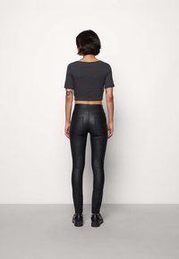 Haut noir court à manches courtes associé à un legging noir taille haute. Texture lisse, coupe ajustée et style minimaliste.