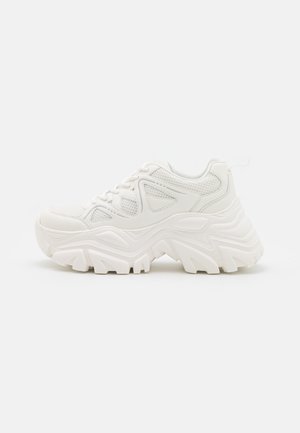 Hvid chunky sneaker med tyk, tekstureret sål, mesh og læderoverdel, snørebånd foran og trækflig ved hælen, vist i sideprofil.