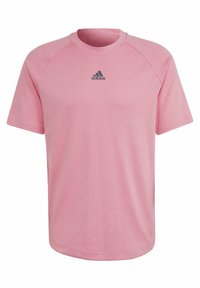 Růžové sportovní tričko s krátkými raglánovými rukávy. Vyrobeno z hladké látky, na hrudi je černé logo Adidas. Kulatý výstřih.