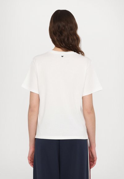 Kurzarm, weißes Baumwoll-T-Shirt mit rundem Halsausschnitt und einem kleinen schwarzen Logo nahe dem Rückenausschnitt, das einen lässigen Schnitt aufweist.