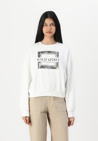 Witte sweatshirt met een grafische print met "WILD SPIRIT" en dierenpatronen. Lange mouwen en geribbelde manchetten, cropped ontwerp.