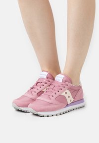 Rosa Saucony Jazz sneakers med mesh- og semsket skinn, rund tå, hvite detaljer, lavendel såle og perforerte detaljer.