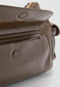 Rjava usnjena torba z gladko teksturo, z zadrgo, okrasnim šivom in okroglo kovinsko dekoracijo.