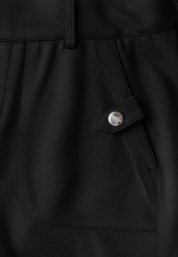Tessuto di pantaloni neri con texture liscia e leggera lucentezza. Presenta una tasca frontale con un bottone in metallo e dettagli di cucitura a contrasto.