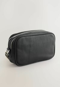 Mustan nahkaisen suorakulmaisen laukun pintakuviointi on tekstuurimainen, ja siinä on kaksinkertainen vetoketju sekä hopeanvärinen metalliosuus sivulla.
