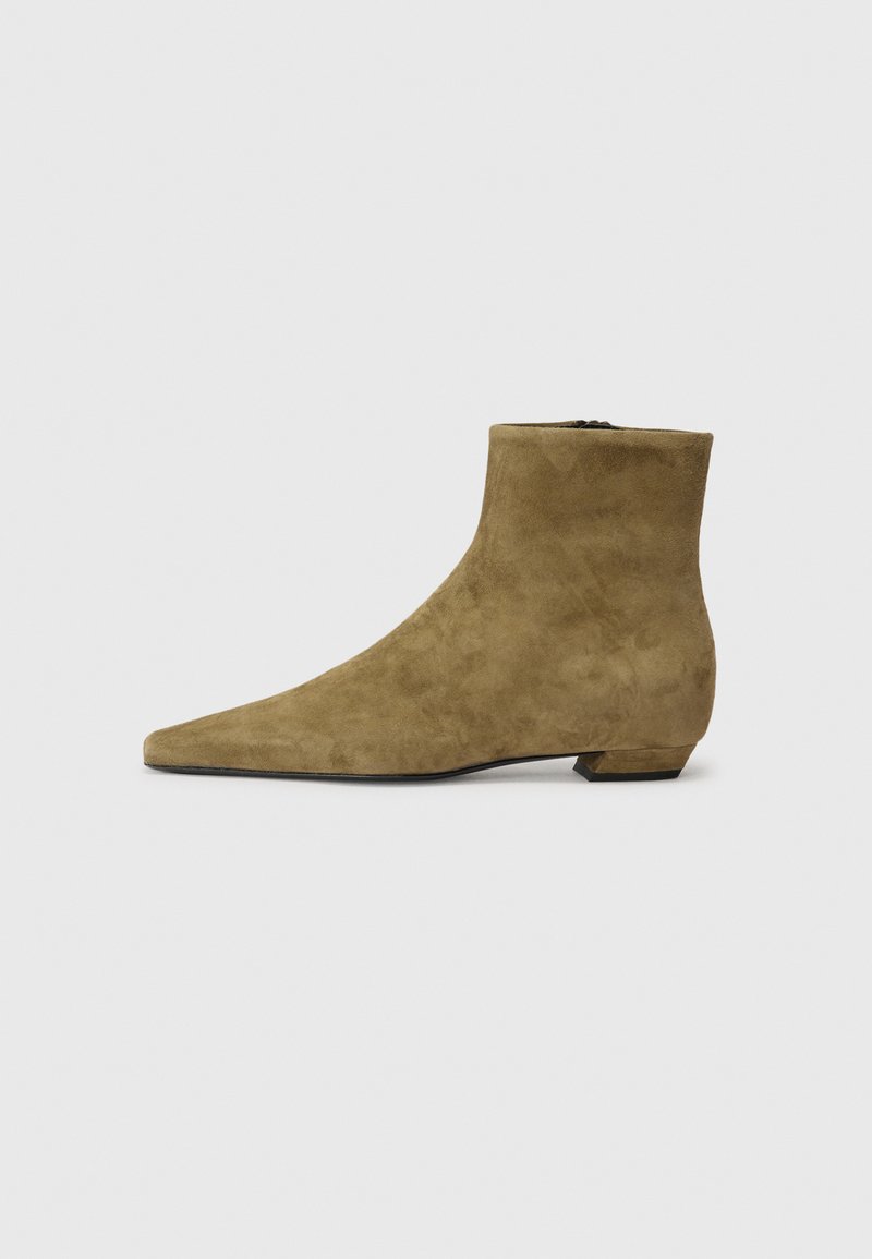 Botas de tobillo de ante verde oliva con un tacón bajo y cuadrado, puntera afilada y una textura suave. Cuentan con una cremallera lateral para facilitar su uso.