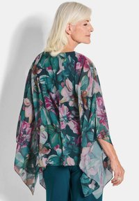 Luftiger, floraler Kimono von der Seite gezeigt; mit einem tealfarbenen Hintergrund und bunten rosa und grünen Blumenmustern; leichtes, durchscheinendes Material.