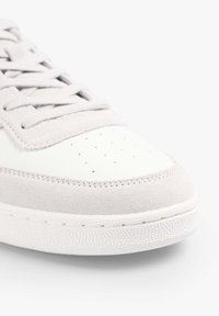 Grijs en witte sneaker met een leren bovenwerk, suède accenten, geperforeerde neus en een gemarmerde rubberen zool. Vetersluiting.