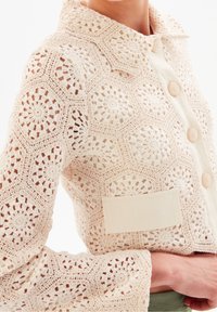 Giacca all'uncinetto color crema con motivi esagonali, grandi bottoni e una tasca a toppa in tessuto semplice a contrasto. Design a maglia aperta e strutturata.