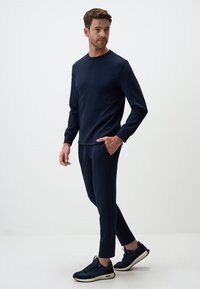 Navy-blaues Sportoutfit, bestehend aus einem langärmeligen Oberteil mit Rundhalsausschnitt und passenden, schmal zulaufenden Hosen, aus weichem Stoff; mit seitlichen Taschen.