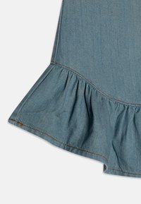 Jeanskjørt med en utsvingt nederkant, med rynkede volanger nederst. Stoffet er lyseblått med kontraststing.