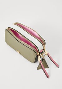 Pochette rectangulaire vert olive avec trois compartiments zippés, quincaillerie dorée, doublure intérieure rose et blanche, et anses roses avec des accents triangulaires.