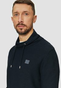 Marineblaues Hoodie mit einem Kapuzenkragen und verstellbarem Kordelzug. Verfügt über einen strukturierten Stoff und ein kleines, rechteckiges Logo auf der Brust.