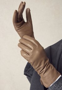 Guanti in pelle marrone con un design aderente, caratterizzati da tre cuciture sul dorso, una texture liscia e un polsino aderente per mantenere il calore.