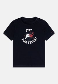 Camiseta de algodón azul marino con un diseño gráfico que muestra el texto "¡MANTEN LA BANDERA FRESCA!" y un personaje de bandera estilizado. Mangas cortas, cuello redondo.