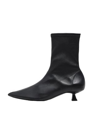 Botín negro hasta el tobillo con parte superior de tela elástica, punta afilada y tacón bajo. Textura lisa con diseño minimalista y sin cierres visibles.