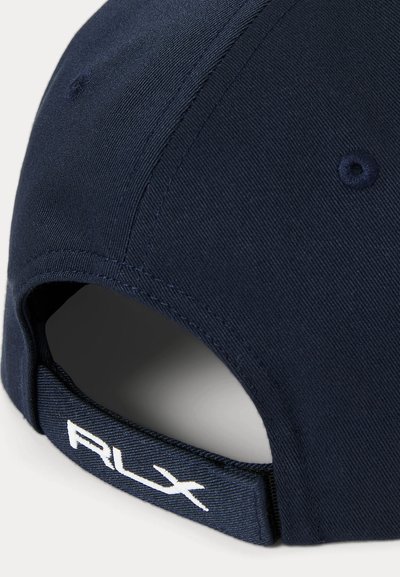 Jūras zila beisbola cepure ar izliekto malu, auduma tekstūra un regulējamu siksnu, kas aizmugurē rotāta ar baltu "RLX" logo.