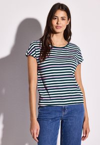 Camiseta de manga corta y cuello redondo con rayas horizontales en verde, blanco y rosa. Tejido suave con un ajuste relajado. Combinada con jeans azules.