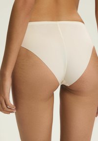 Beżowe majtki z wysokim stanem o gładkim wykończeniu, z miękkim pasem w talii i minimalnymi szwami dla efektu bezszwowego wyglądu.